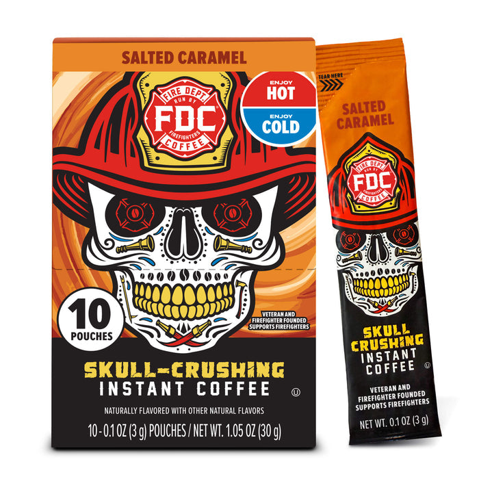 FCD Fire Department Salted Caramel Instant Coffee packaging, showing a 10-count box alongside a single stick pouch. The design features a skull wearing a firefighter helmet with a red, orange, and black color scheme and a blue 'Enjoy Hot or Cold' badge.