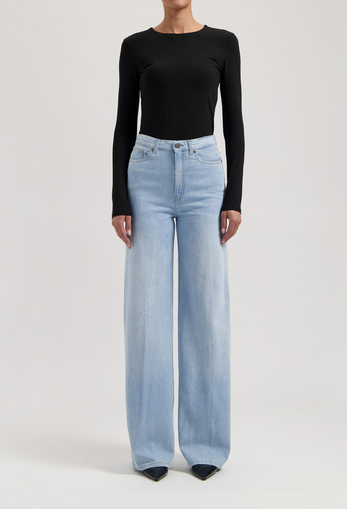 Wide-leg light blue jeans paired with a sleek black long-sleeve top, showcasing modern casual fashion.