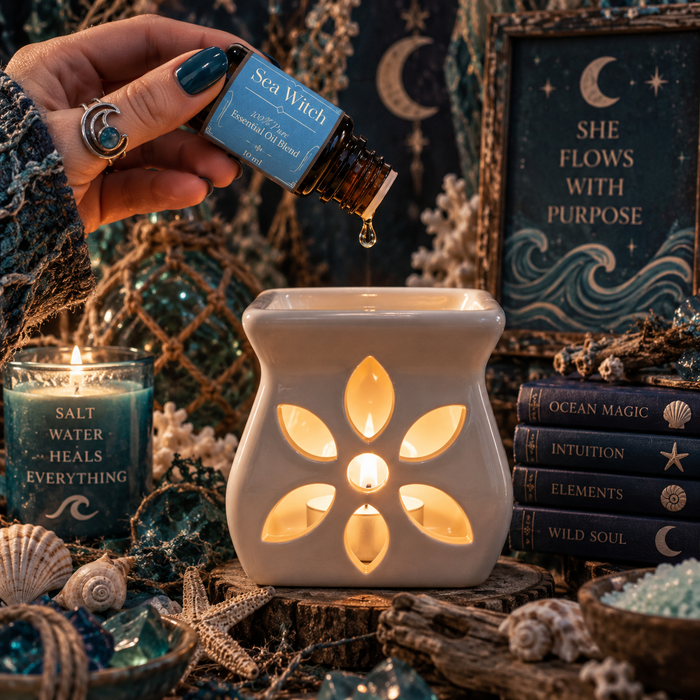 Sea Witch diffuser blend being poured into an essential oil burner on a wooden surface surrounded by seashells with blue crystals and candles in the background