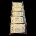 Five clear plastic bags of witchy herbs for love spells and rituals stacked vertically on a black background. The labels read Daminia, Motherwort, Vervain, Patchouli, and Rose Petals, with floral illustrations and common ritual uses printed on the cream-colored labels.