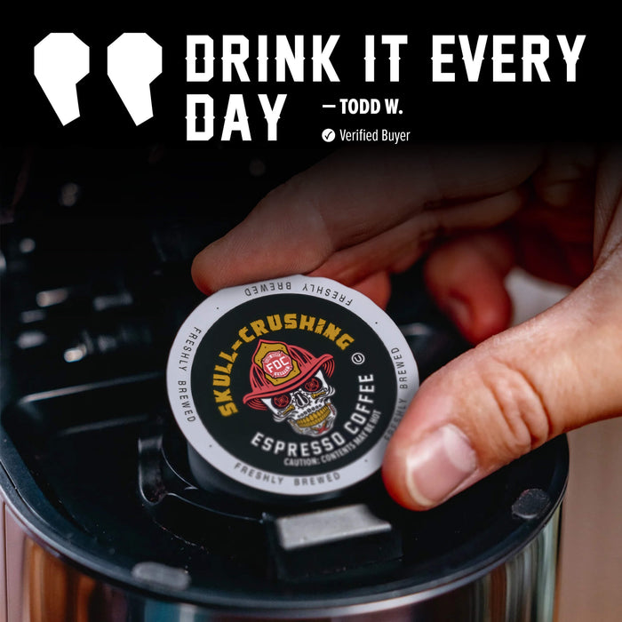 A hand inserts a single round coffee pod into a black coffee maker. The pod is branded Skull-Crushing Coffee and reads 'Espresso Coffee.