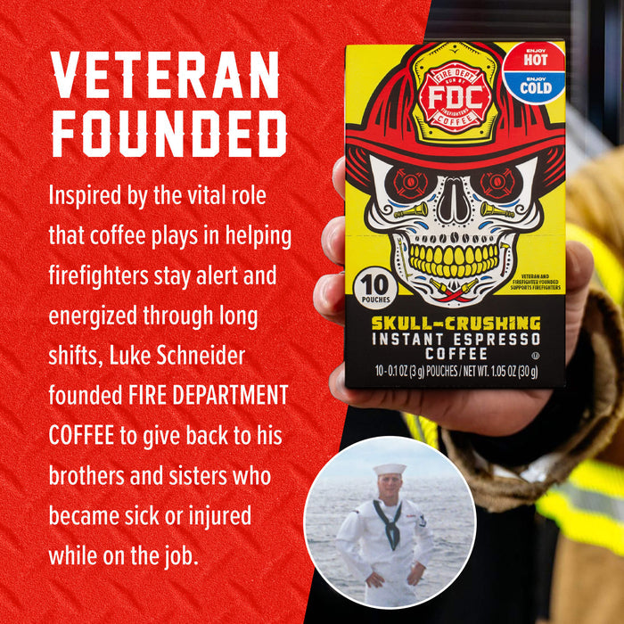 A hand holds a box of Fire Department Coffee 'Skull-Crushing' Instant Espresso Coffee against a red textured background with white text. The box features a yellow and black design with a skull wearing a firefighter helmet.