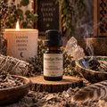 Smudge Blend essential oil diffuser blend on a wooden surface with a feather and white sage smudge sticks with a candle in the background