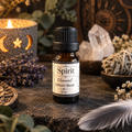 A 10 ml amber glass bottle of 'Spirit Elemental Diffuser Blend' with a black cap and cream label, styled on a dark stone surface with a lit candle, lavender, crystals, and a feather.