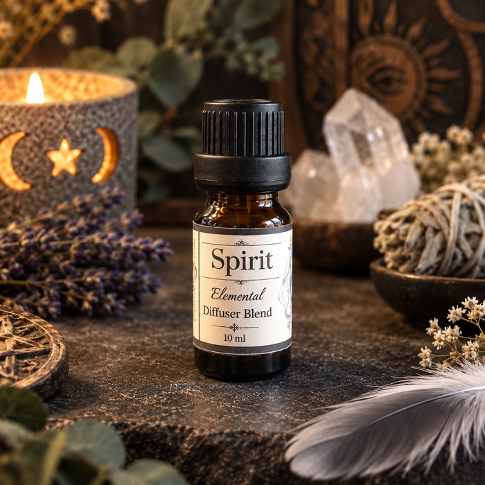 A 10 ml amber glass bottle of 'Spirit Elemental Diffuser Blend' with a black cap and cream label, styled on a dark stone surface with a lit candle, lavender, crystals, and a feather.