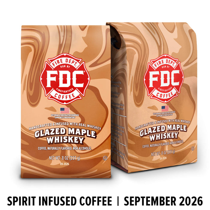 Two bags of FDC Fire Department Bar Coffee Glazed Maple Whiskey coffee with a brown liquid swirl design, shown on a white background with a black text banner at the bottom reading 'SPIRIT INFUSED COFFEE | SEPTEMBER 2026'.