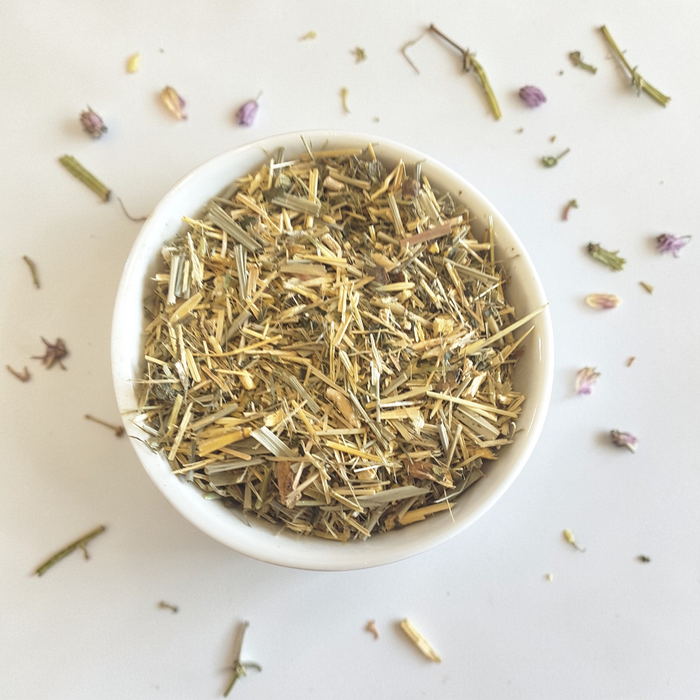 Strength & Boundaries Emotional Wellness Tea on a light surface with scattered herbs around