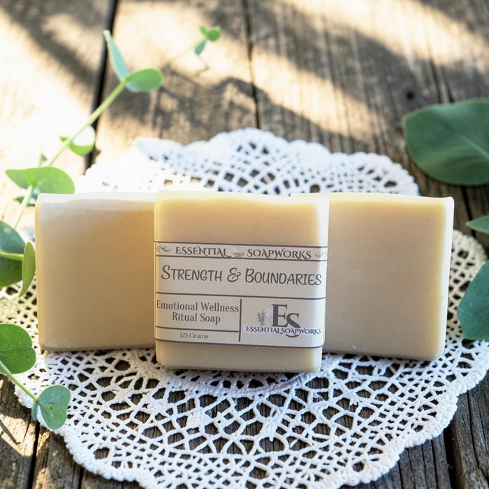 Strength & Boundaries Emotional Wellness Soap on a white doily, surrounded by green leaves on a wooden surface.