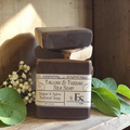 tallow soap on a wooden surface with green leaves and white flowers