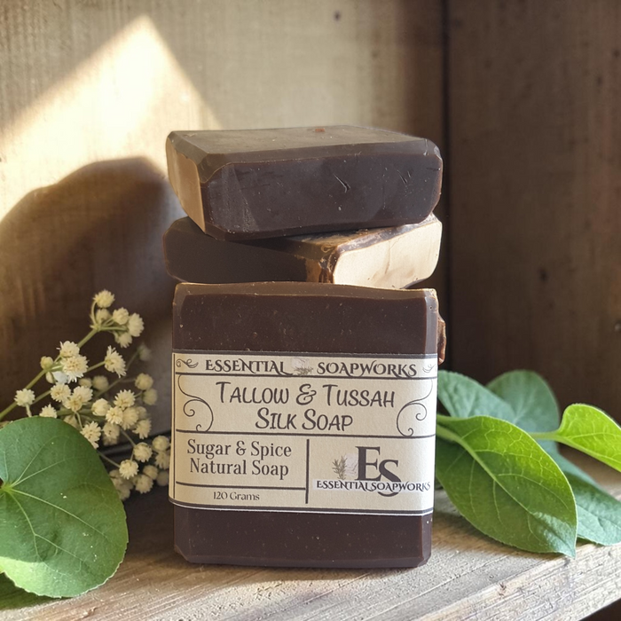 tallow soap on a wooden surface with green leaves and white flowers
