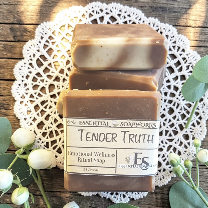 Tender Truth Emotional Wellness Soap on a wooden surface with flowers in the background