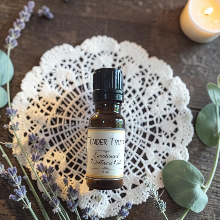 Tender Truth Emotional Wellness Oil on a doily on a wooden surface with lavender and eucalyptus