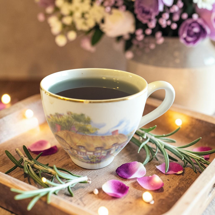 third eye tea on a wooden tray with rosemary and petals, blurred flowers in the background