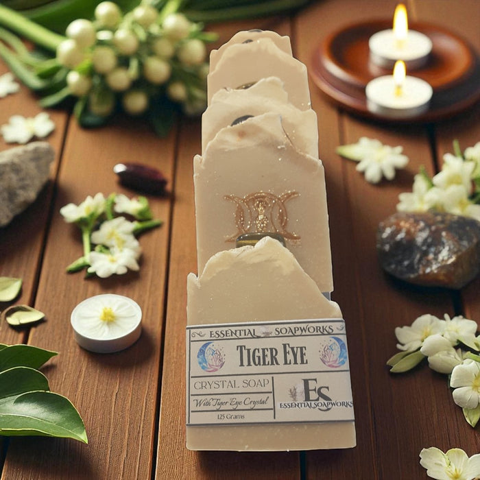 Tiger Eye crystal soap with a triple goddess symbol on a wooden surface with flowers and candles.