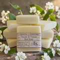 unscented tallow soap on a wooden surface with green leaves and white flowers
