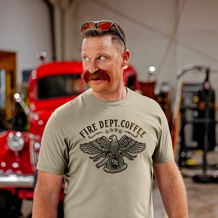 Man wearing a 'Fire Dept. Coffee' t-shirt in a fire station with a vintage red truck in the background.