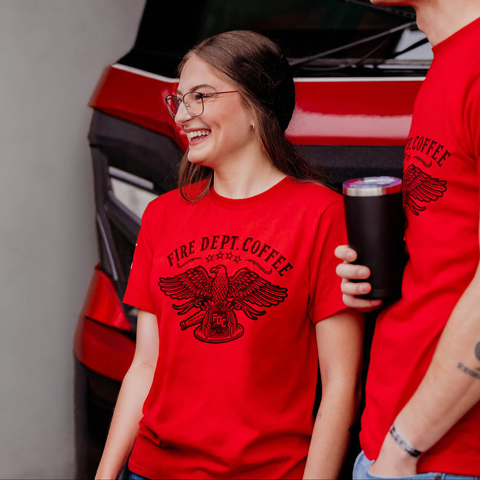 Two people wearing red 'Fire Dept. Coffee' t-shirts with a coffee cup in front of a red fire truck.