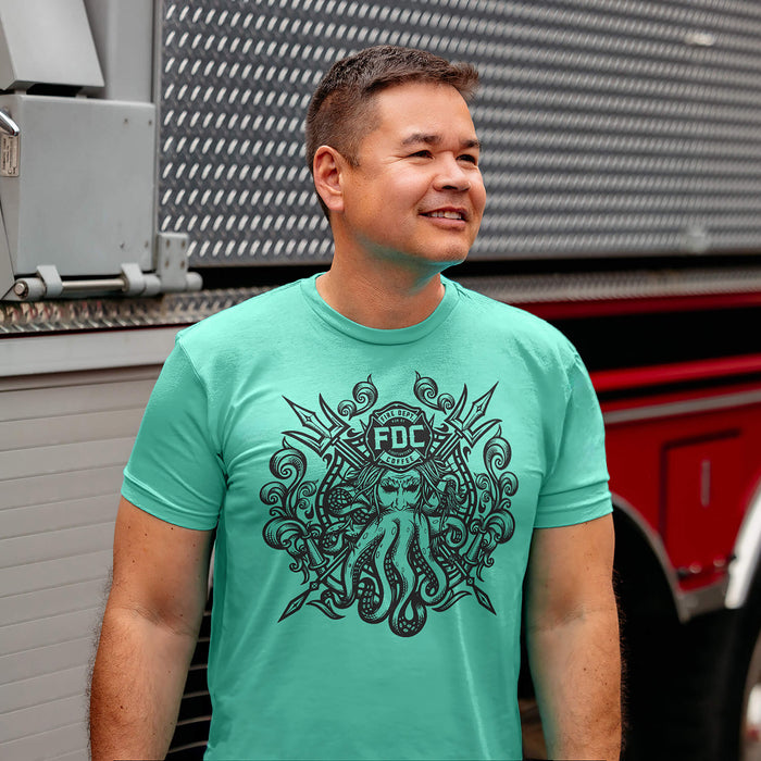 A man wearing a mint Fire Dept. Coffee T-shirt featuring a large black Shellback-inspired graphic with an FDC logo and octopus design on the front, standing beside a fire truck outdoors